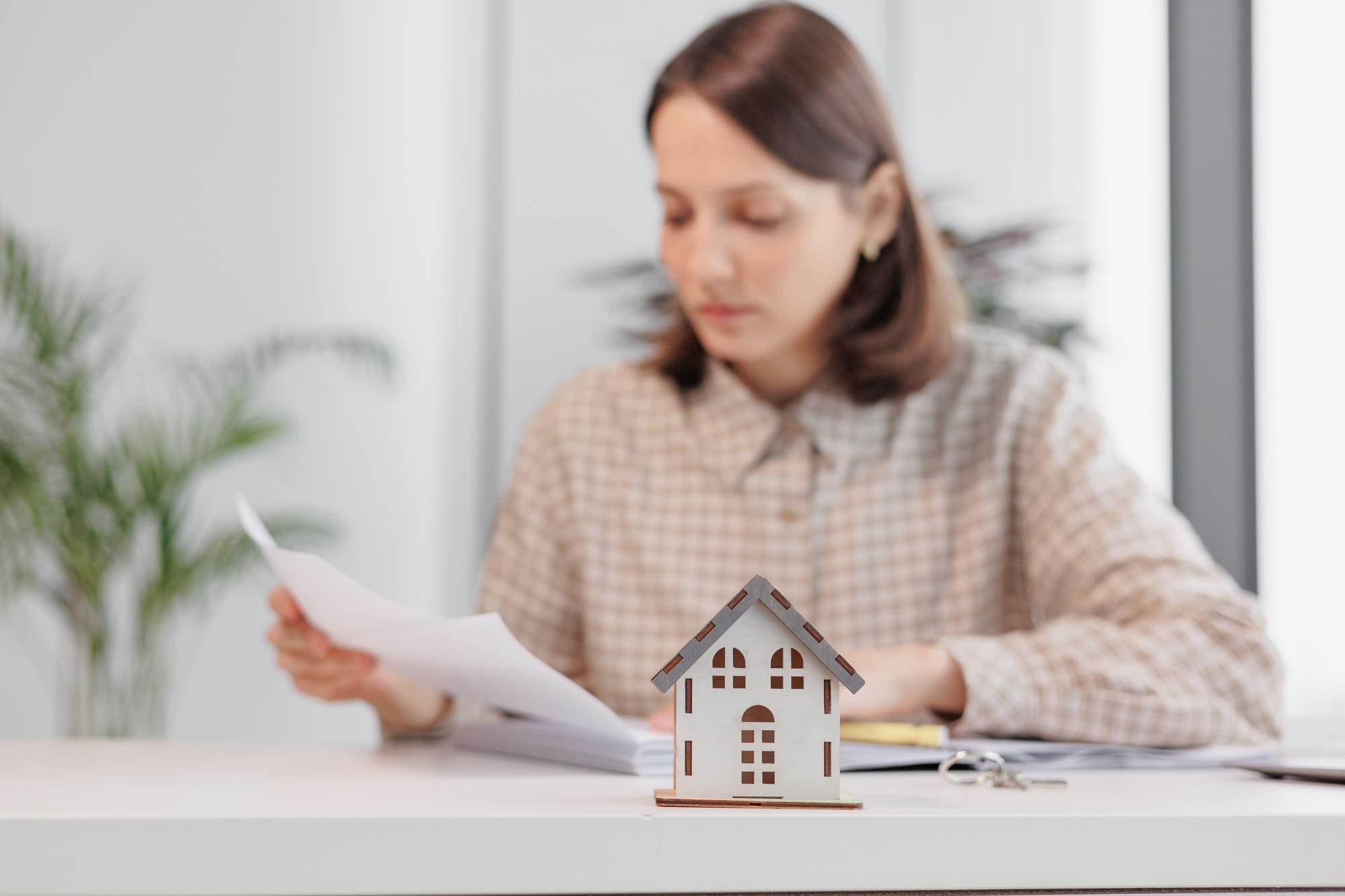 a miniature model of the house and keys in her hands. sale of real estate. the designer communicates