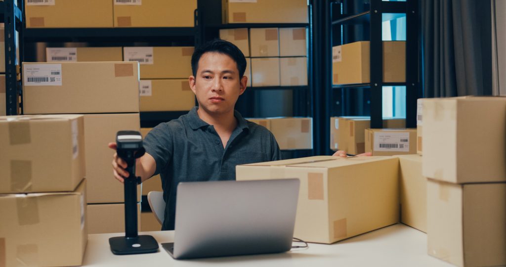Asian businessman use barcode machine scan customer data in paper box and type register online.