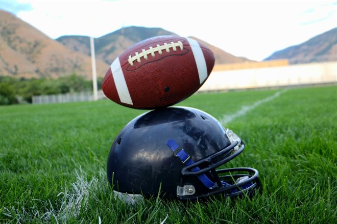 Balancing life and football, conceptual color image of football balancing on helmet.