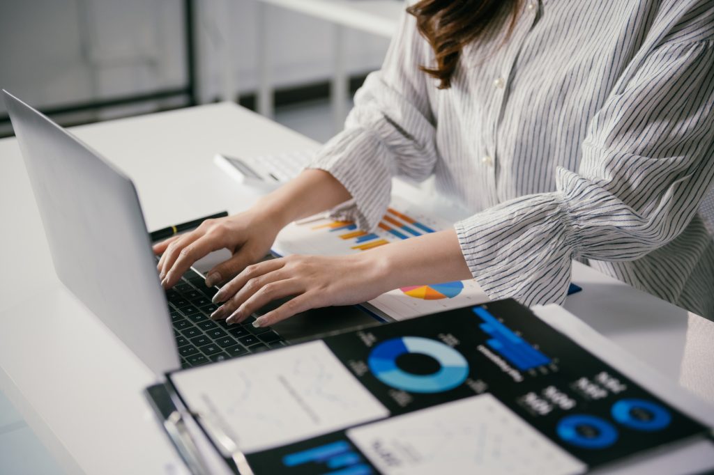 Businesswoman is working with financial data, analyzing charts and typing on a laptop, developing a