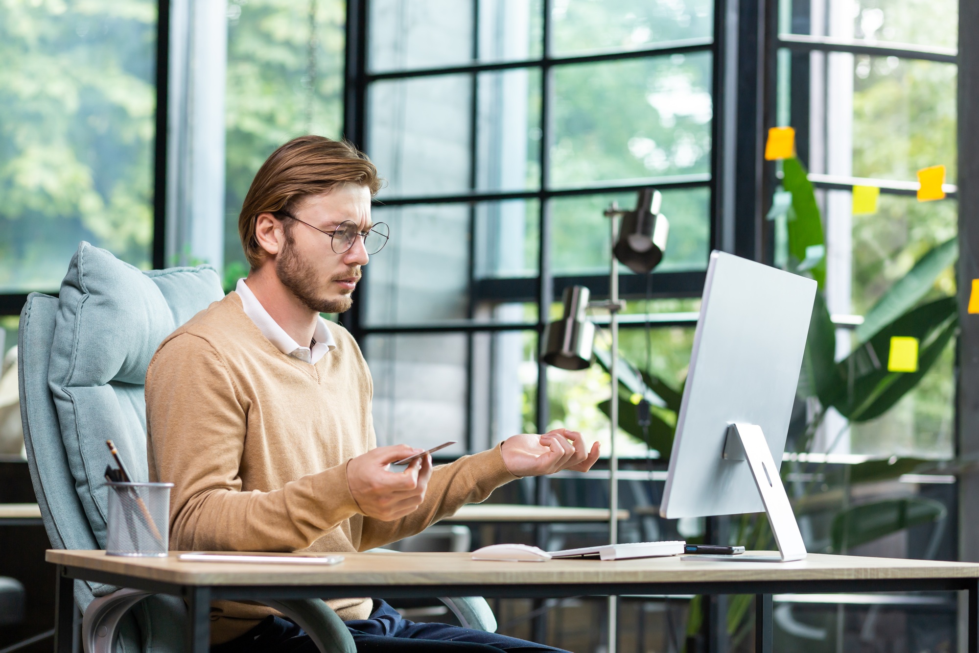 Financial problems. A young male businessman is sitting at a desk in the office and looking