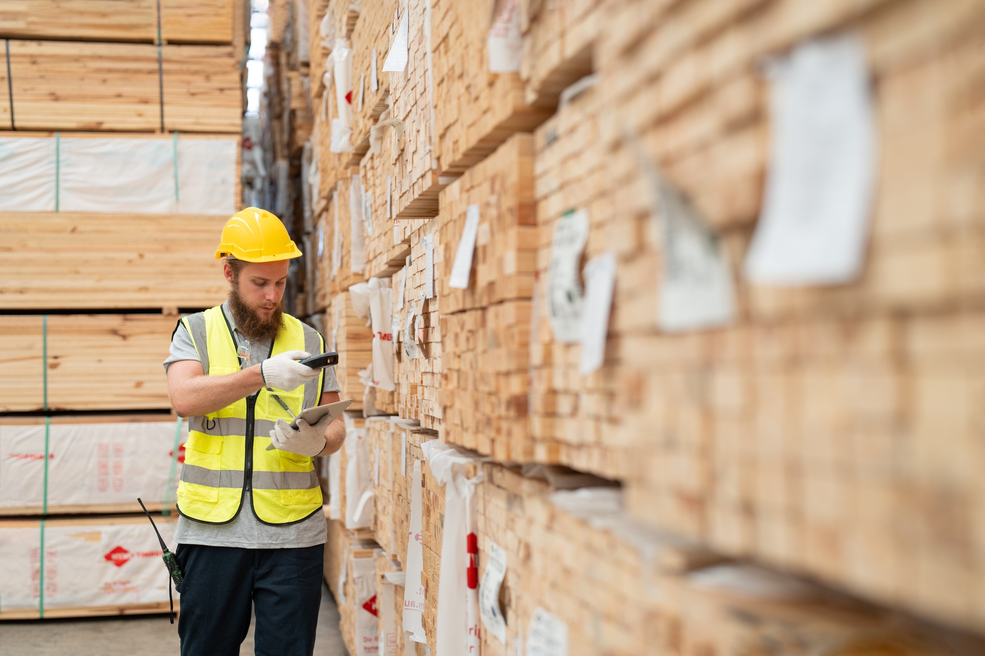 Male worker using scanner machine scanning barcode on label  checking plank wood stock at warehouse