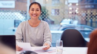 Portrait Of Smiling Asian Businesswoman Sitting At Table In Office  Meeting Room