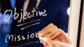Smart business man writing the word Objective Mission on the mirror board